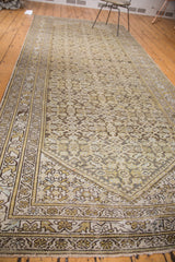 Distressed Hamadan rug corner with faded Herati pattern in ivory, green, charcoal.
