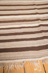 Striated hand-woven texture in natural beige and brown tones with delicate fringe.