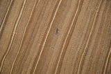 Striated beige and brown flat weave of the vintage Kilim, showing a small mend.
