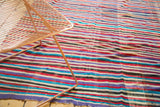 Textured detail of colorful striped vintage Kilim, showing oblique weaving with wine, aqua, and violet hues.