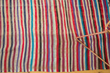 Angled close-up of colorful Moroccan kilim, featuring randomly alternating stripes and woven texture.