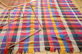 Hand woven Moroccan plaid throw rug with vibrant fuchsia, violet, yellow stripes, and colorful fringe.