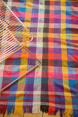 Close-up of vintage Moroccan plaid textile showing vibrant fuchsia, yellow, aqua, violet, and multi-colored fringes.