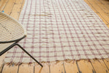 Textured hand-woven Moroccan plaid textile with wine red and ivory stripes, showing fringe.