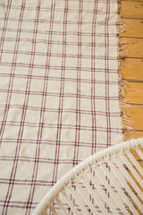 Plaid pattern of the vintage Moroccan textile with wine red and ivory stripes and fringed edge.