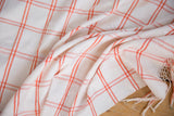 Hand woven peach-orange and ivory plaid texture with fringed edge on vintage Moroccan textile.