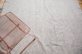 Ivory hand woven Turkish vintage flatweave carpet detail, showing charcoal speckles and small hole.