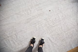 Hand-woven vintage flatweave rug with ivory and charcoal textured surface, showing small hole.