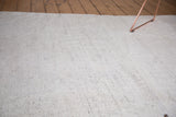 Close-up of ivory Turkish flatweave, revealing a secured hole and charcoal flecks.