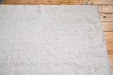 Ivory vintage Turkish flatweave carpet texture, showing charcoal foundation and rustic edge.