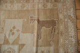 Geometric animal motif in sand and ivory tones on a vintage hand knotted rug.