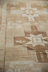 Geometric bronze and ivory starburst pattern with serrated border on a vintage Oushak rug.