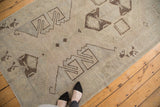 Minimalist geometric motifs in charcoal brown on faded blanched tones of a vintage Oushak rug.
