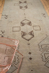 Textured hand knotted Oushak runner with charcoal brown geometric patterns on a faded pastel ground.