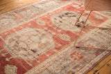 Octagonal medallion with trefoil, faded tangerine, ivory, and charcoal patterns on the Oushak rug.