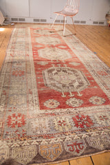 Close-up of vintage Turkish Oushak runner's cherry red field with floral elements and geometric border.