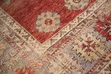 Vintage Oushak rug corner detail with cherry red, ivory, and charcoal geometric-floral patterns.