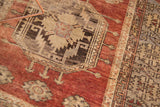 Vintage Oushak rug close-up: cherry red field, octagonal motif, saffron, charcoal, ivory patterns.