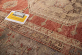 Detail view of vintage Oushak rug: faded tangerine, ivory, grey floral motifs, hand-knotted pile.