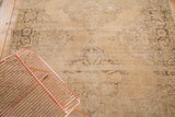 Distressed beige field with faded charcoal medallion patterns and abrash.