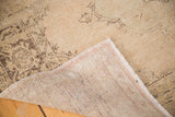 Vintage Sparta rug's folded corner, revealing beige pile with charcoal pattern and woven foundation.