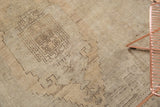 Beige field with brown geometric pattern and heavy abrashes on a vintage Oushak rug.
