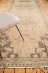 Vintage Oushak runner showing its cream and charcoal primitive geometric patterns and fringe.
