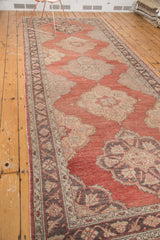 Ornate charcoal border with floral motifs and scalloped pale gold medallion on red field.