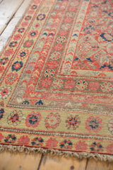 Distressed Malayer rug corner, with worn pile texture, bright floral motifs, and secure fringe.