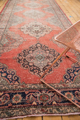 Repeating medallion on a distressed Sparta runner, cinnabar field, time-softened hues.
