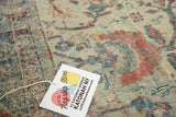 Close-up of distressed antique Mahal carpet pile with faded floral motifs and flagship store tag.