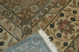 Distressed vintage Romanian carpet corner, showing faded bronze florals, white fringe, and striped woven reverse.