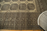 Distressed Afghan carpet showing multi-repeating geometric borders in faded ivory and charcoal.