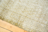 Distressed Malayer rug surface with faded ivory, pale sage gold, and charcoal abrash.