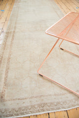 Faded hexagonal motif and secure fringe detail of the distressed beige Oushak runner.