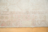 Secured side edge and distressed pile of a vintage Oushak rug with blush hexagonal motifs.