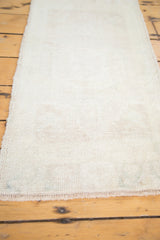Short, even pile of a vintage Oushak rug mat in pale sand, ivory, and delicate fringe.