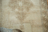 Vintage Oushak rug close-up: hand-knotted pile, subtle patterns, pale wooded tones, and folded blue backing.