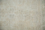 Textured close-up of the distressed Oushak rug pile, featuring soft beige and silver.