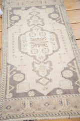 Oushak rug detail: pearl motif on pale ivory field with charcoal geometric spandrels.