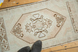 Oversize geometric medallion with pale blush and chocolate brown tones on a vintage Oushak runner.