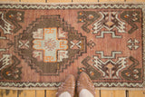 Asymmetric vintage Oushak rug with a stepped medallion and bronze, orange, ivory motifs.
