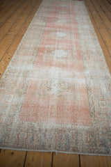 Faded blush and ivory medallion patterns on the distressed pile of this Oushak runner.