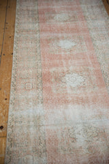Faded blush field and ivory medallion texture on a distressed Oushak runner.