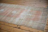 Distressed blush field and ivory border texture of a vintage Oushak runner.