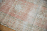 Distressed blush Oushak runner texture with soft ivory and silver floral motifs.