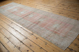 Distressed texture and blush tones on the secured edge of a vintage Oushak runner.