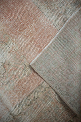 Distressed blush and ivory pile of a vintage Oushak rug, revealing its woven foundation.