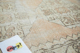 Distressed pile of an Oushak rug with primitive geometric patterns in ivory, blush, and apricot.