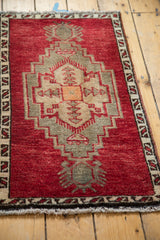 Thick pile on the geometric central medallion, cherry red, charcoal, and tangerine tones.
